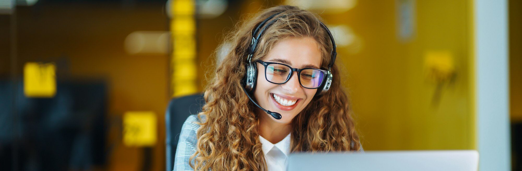 Call center agent with headset working on support hotline in modern office. Video conference.